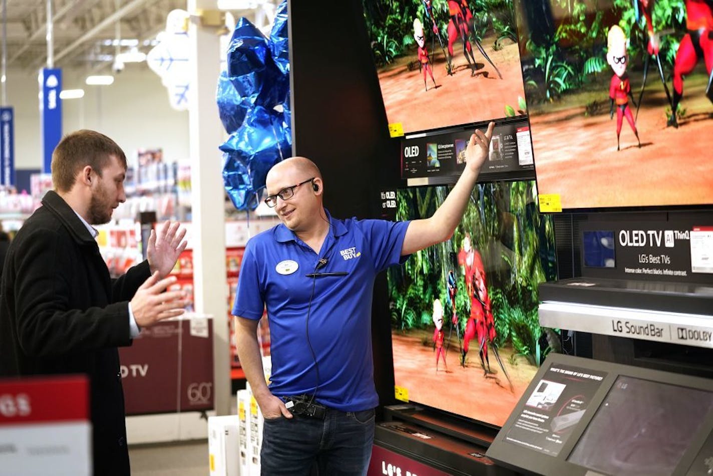 Best Buy sales consultant Jon Hollywood talked with customer Josh Watson, left, who was visiting from Midland, Michigan, about television options.