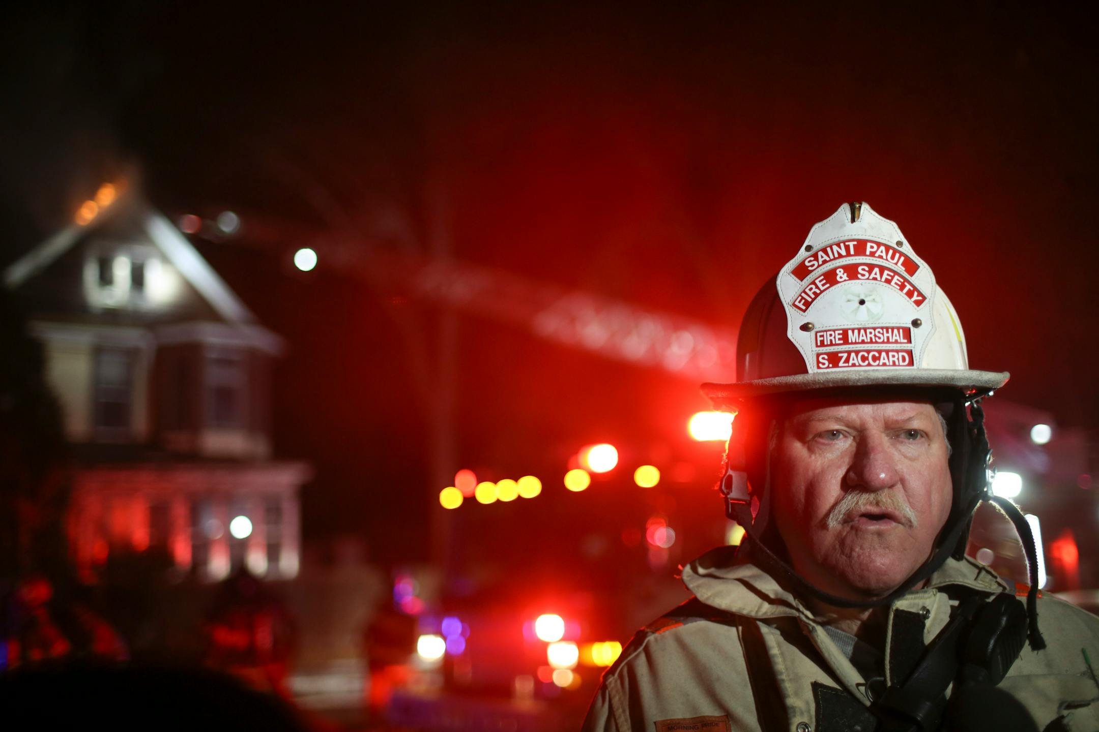 St. Paul Fire Marshall Steve Zaccard talked to reporters while firefighters battled stubborn flames in the attic of the house at 599 E. Jessamine Av. behind him Sunday night.