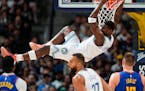 Timberwolves guard Anthony Edwards hangs from the rim after dunking the ball for a basket in the first half against the Nuggets on Friday in Denver.