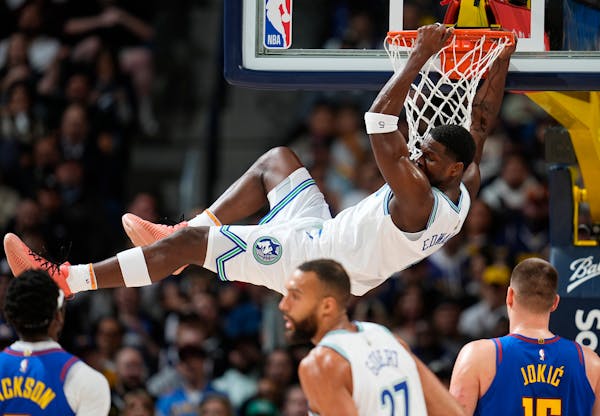 Timberwolves guard Anthony Edwards hangs from the rim after dunking the ball for a basket in the first half against the Nuggets on Friday in Denver.