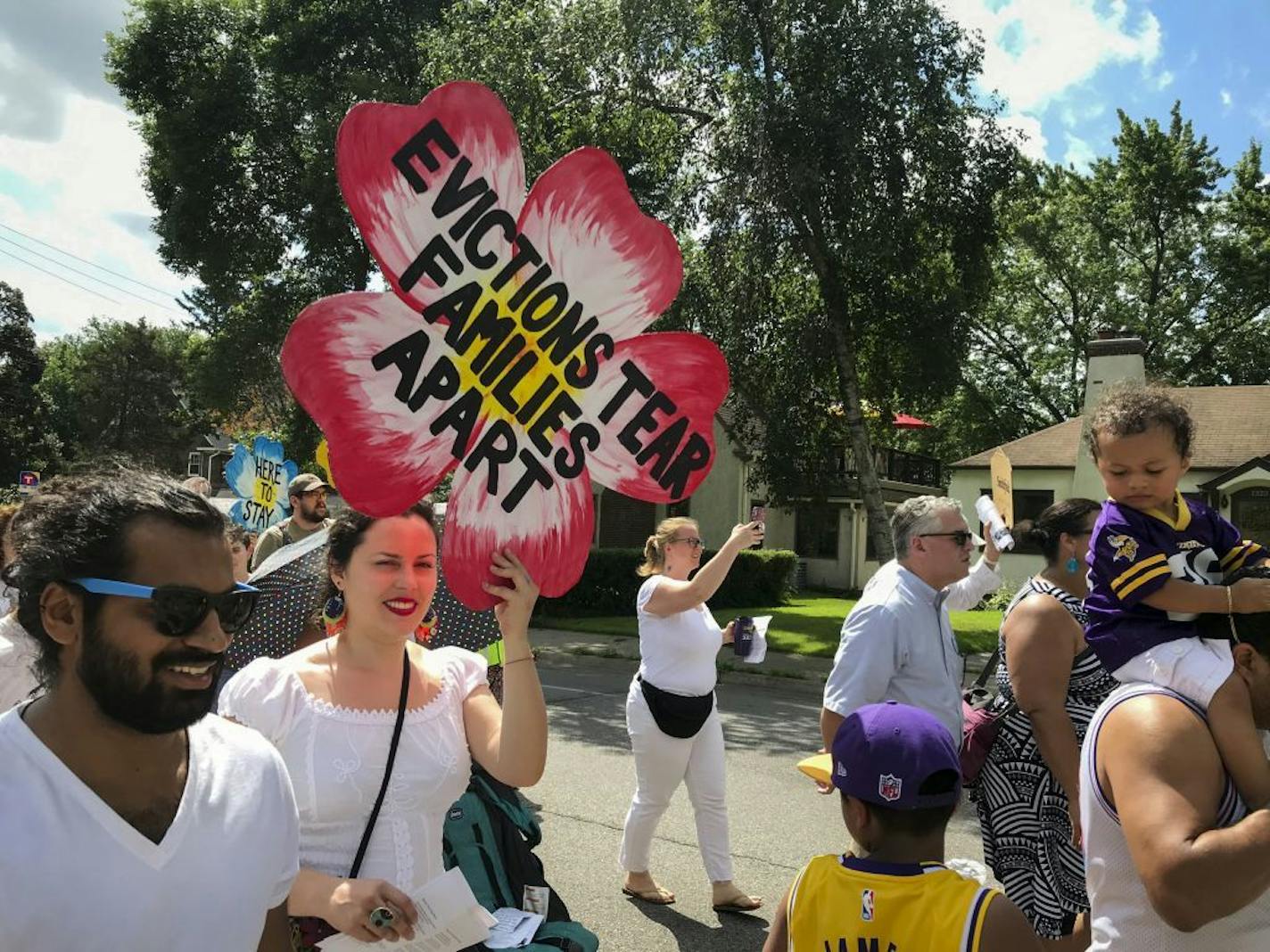 Tenants and their supporters marched to Our Lady of Peace Church in south Minneapolis to oppose the efforts by one of the parishioners, landlord Stephen Frenz, to evict tenants from about 40 apartment units at five buildings in Minneapolis, Minn. Sunday, July 14, 2019. Jennifer Arnold, holding the sign, is a leader in Inquilinxs Unidxs (United Renters for Justice) which organized the protest.