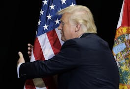 Republican presidential candidate Donald Trump pauses during his campaign speech to hug the American flag Saturday, June 11, 2016, in Tampa, Fla. (AP 