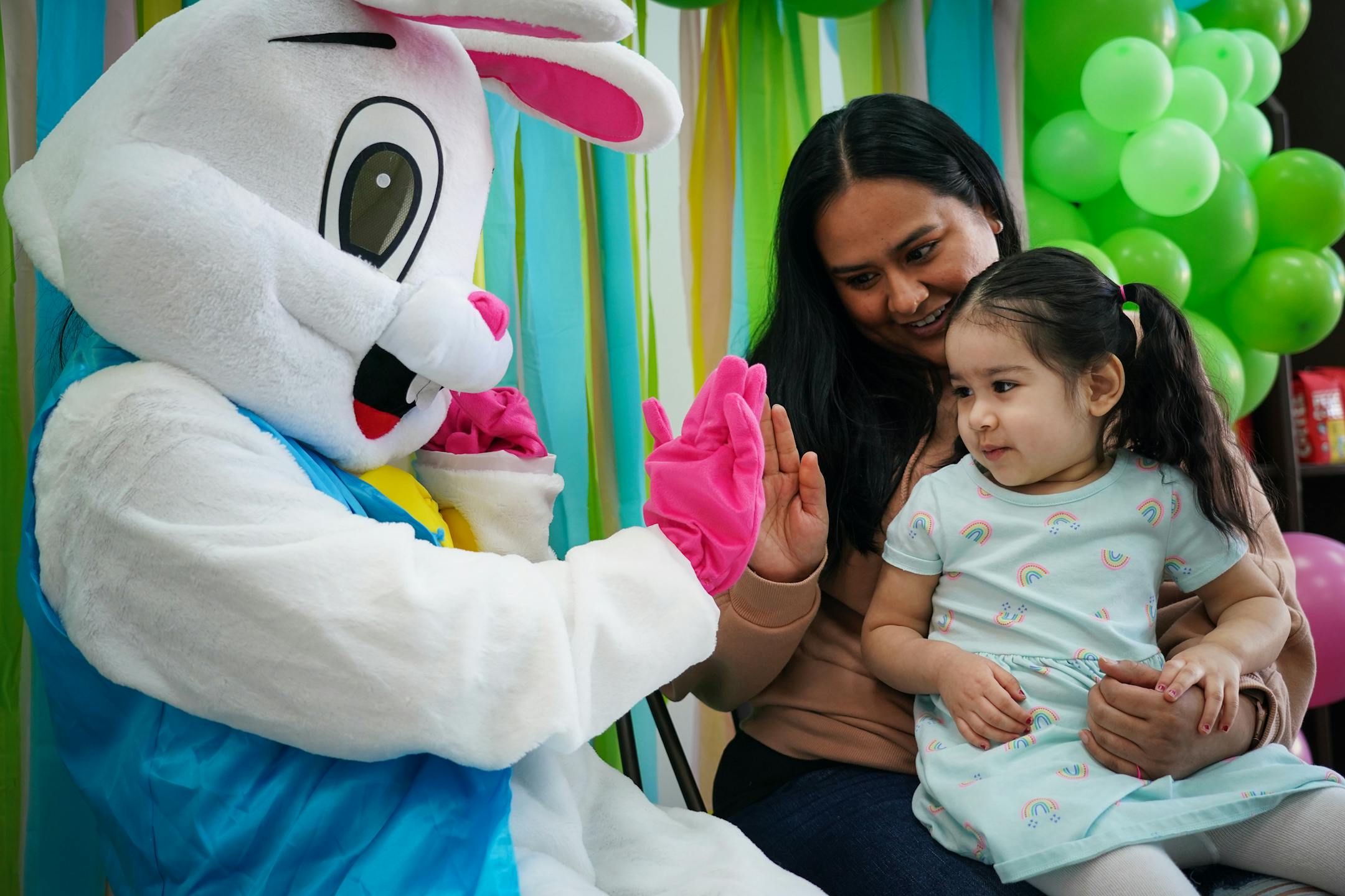 The Easter Bunny gives a high-five to Marlene Orozco while her daughter Desiree, 2, is a wee bit apprehensive of the giant hare.