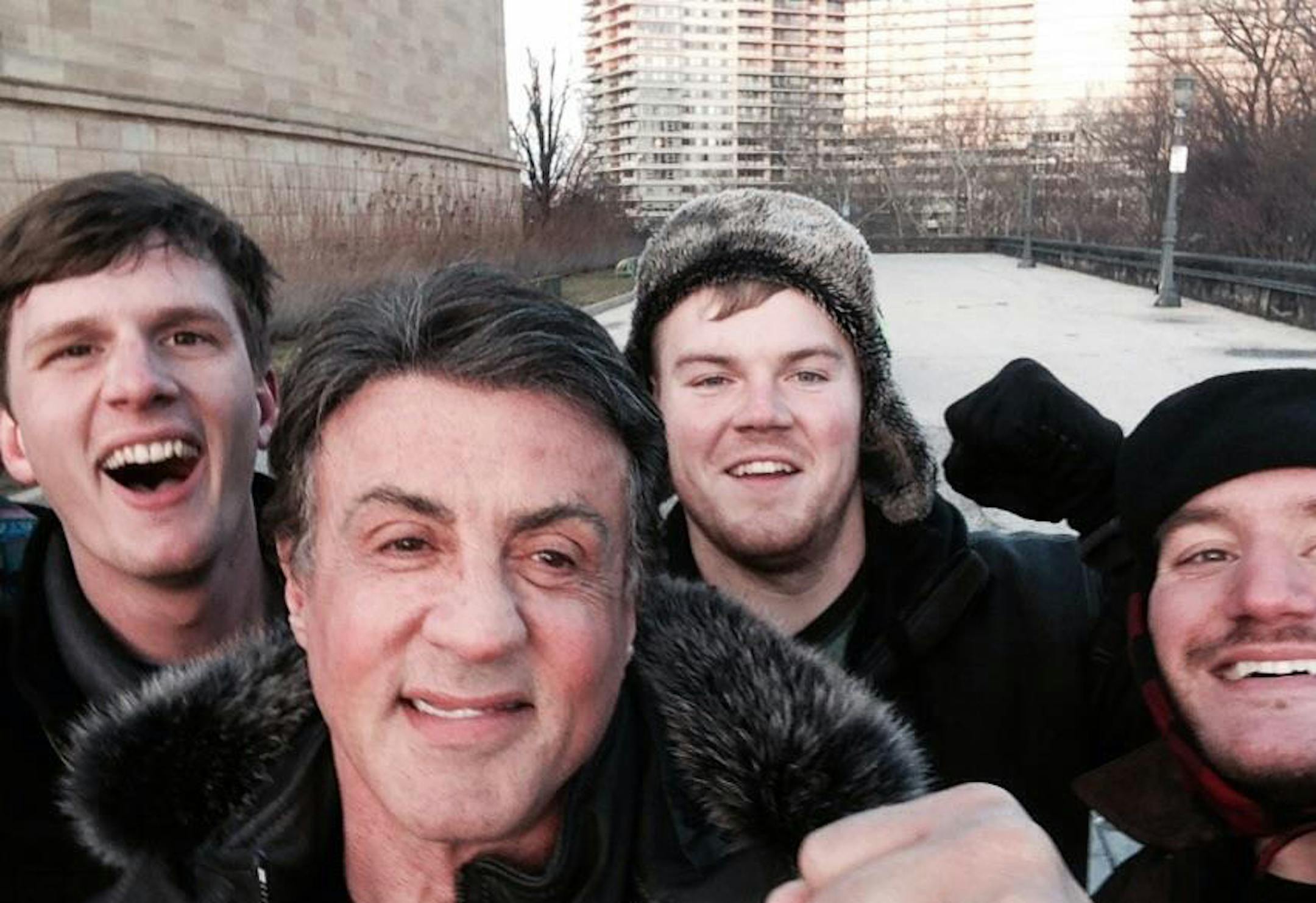 In this Jan. 17, 2015, photo provided by Peter Rowe, Rowe, right, takes a selfie with friends Jacob Kerstan, left, Andrew Wright, third from left and actor Sylvester Stallone in Philadelphia. Rowe said the three friends had just finished racing up the staircase at the city's Museum of Art when they saw Stallone. Stallone made the steps famous in his first turn as fictional boxer Rocky Balboa, who used them as part of his training regimen. Thousands of people now visit the steps each year to re-c