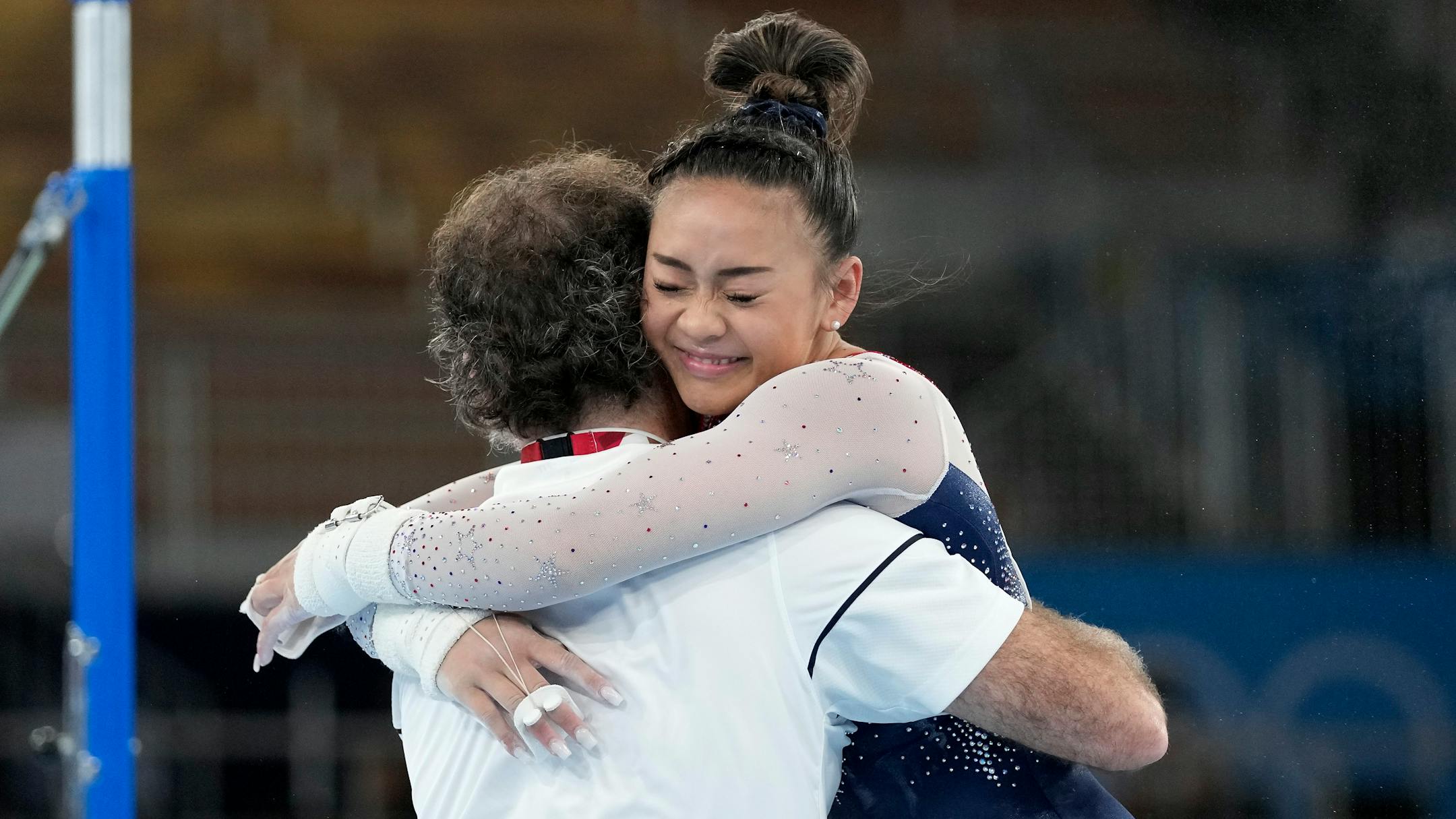 Suni Lee, of the United States, embraces her coach Jeff Graba after performing on the uneven bars during the artistic gymnastics women's all-around final at the 2020 Summer Olympics, Thursday, July 29, 2021, in Tokyo. (AP Photo/Gregory Bull)