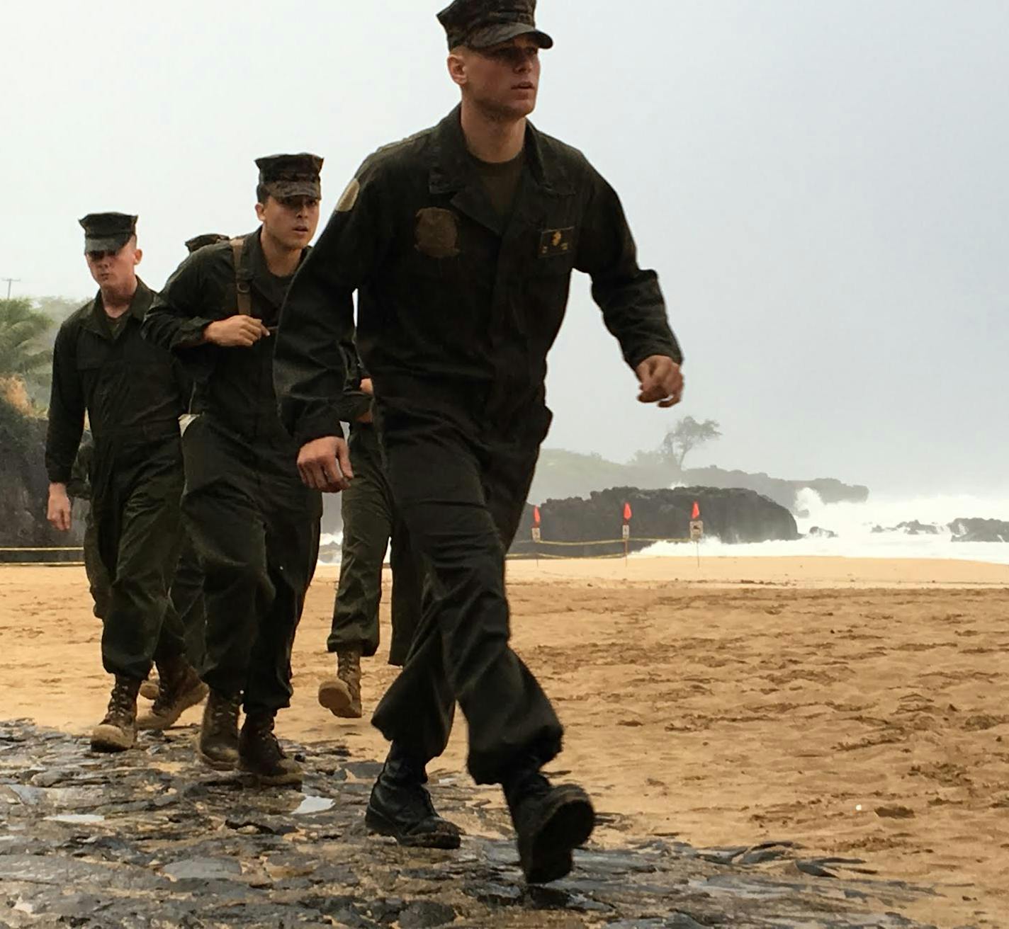 U.S. Marines walk on the beach at Waimea Bay near Haleiwa, Hawaii, where two military helicopters crashed into the ocean about 2 miles offshore, Friday, Jan. 15, 2106. The helicopters carrying 12 crew members collided off the Hawaiian island of Oahu during a nighttime training mission, and rescuers are searching a debris field in choppy waters Friday, military officials said. (Mariana Keller via AP Photo)