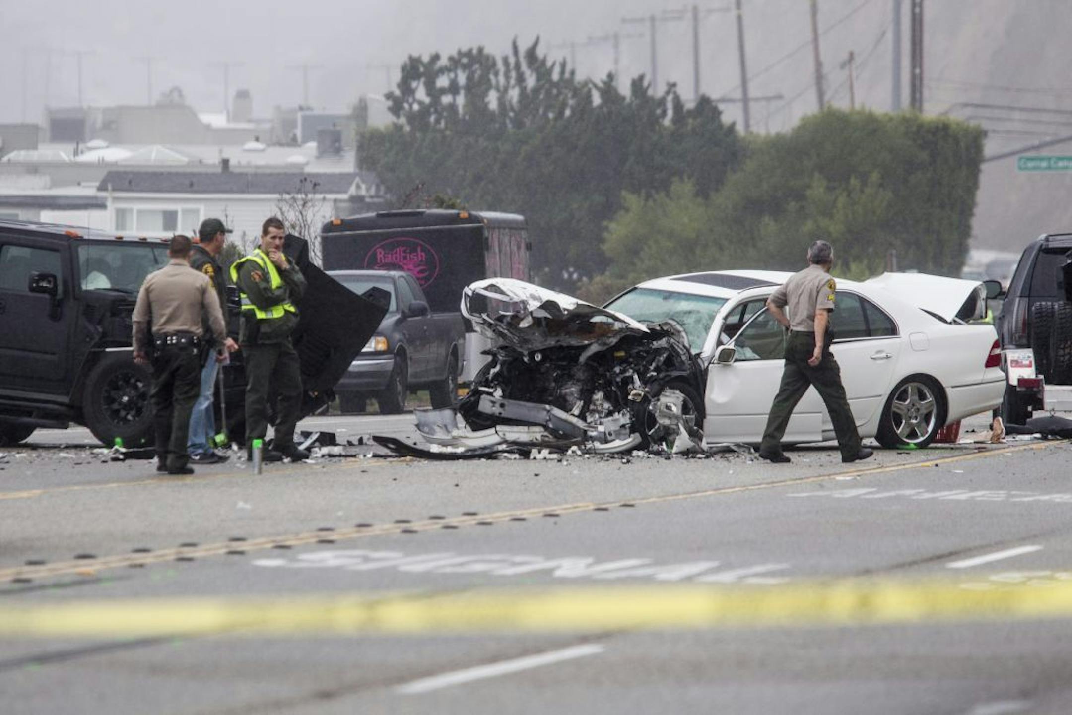 Los Angeles County Sheriff's deputies investigate the scene of a collision involving three vehicles in Malibu, Calif. on Saturday, Feb. 7, 2015. Officials said former Olympian Bruce Jenner was a driver of one of the cars involved in the Pacific Coast Highway crash that killed one person. Jenner's publicist, Alan Nierob, says Jenner was unhurt.