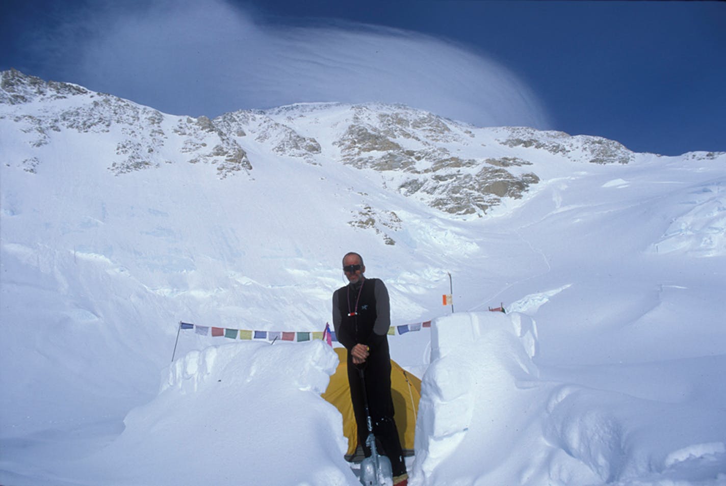 Mike Farris at 14,100 feet on Denali, with fierce winds over the summit behind.