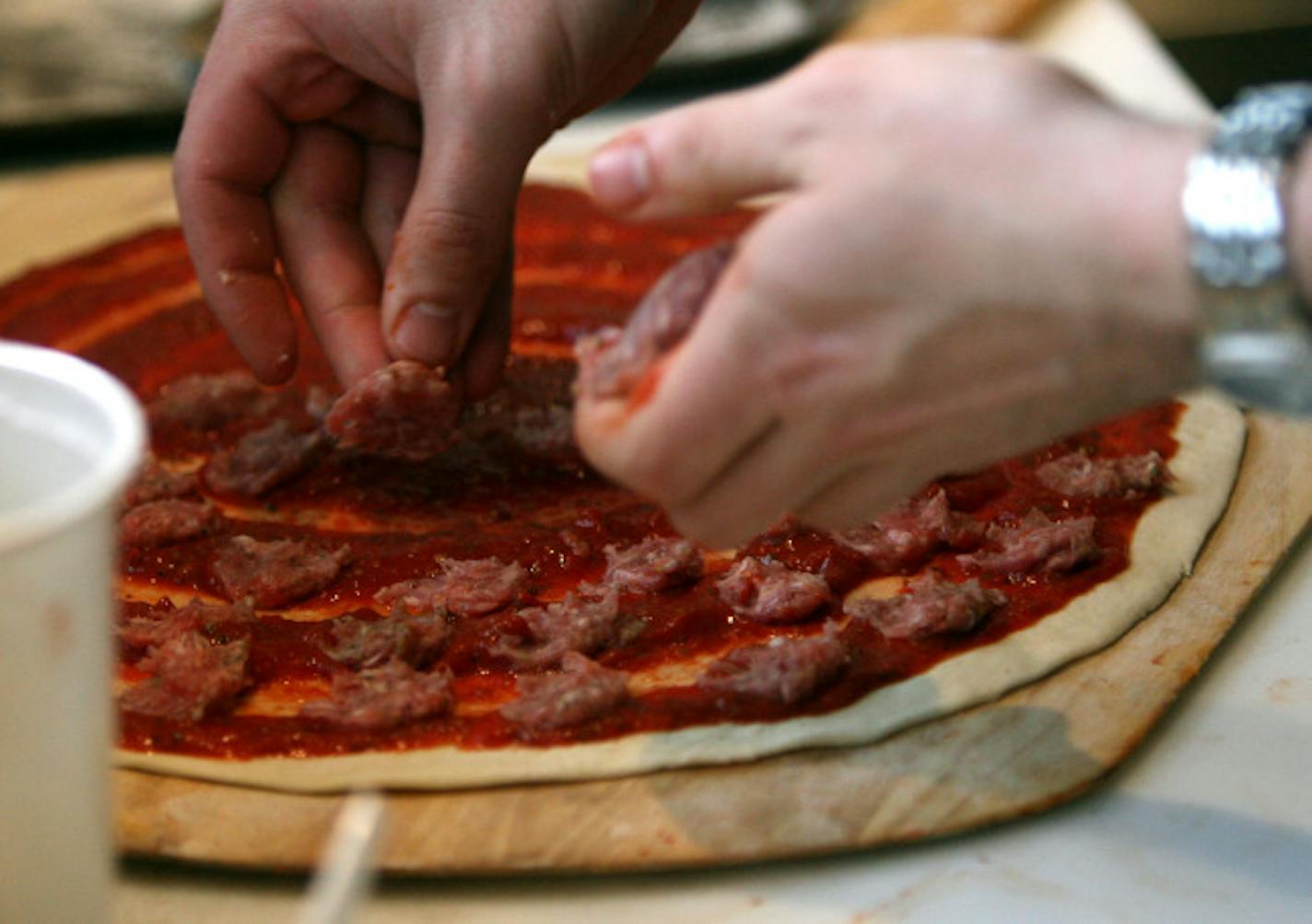 Mamas employee Matty Hedgepeth loads a pizza with sausage over the lunch hour at Mamas Pizza in St. Paul. After being closed for 11 months north end landmark Mama's Pizza is open for business. "It's like our customers are a big, giant family," said Tony Mudzinski, part-owner. "You tell one person and then everyone knows." Mudzinski said that shortly after the restaurant opened at 4 p.m. Saturday, the place quickly filled up and friends stepped up to shuffle people in and out, with some customers