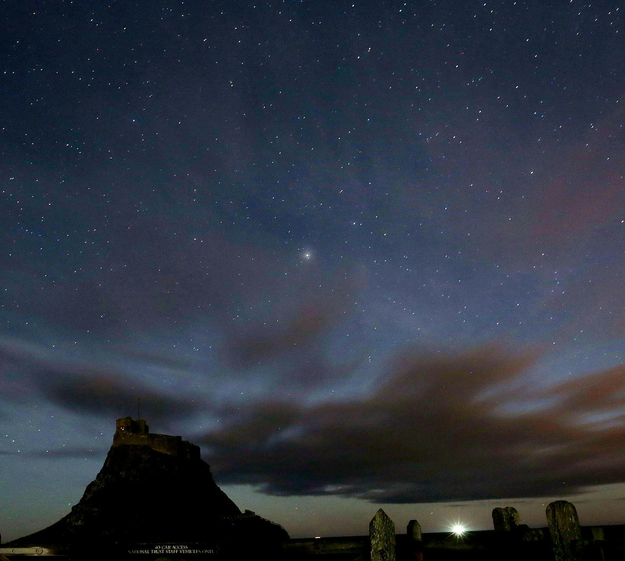 FILE- This Jan. 9, 2014, photo shows, a view of the stars above Lindisfarne Castle in Holy Island, England, Thursday, Jan. 9, 2014. Scientists reported Thursday, Nov. 6, 2014, that as many as half of all stars may lie outside galaxies. (AP Photo/Scott Heppell, File)