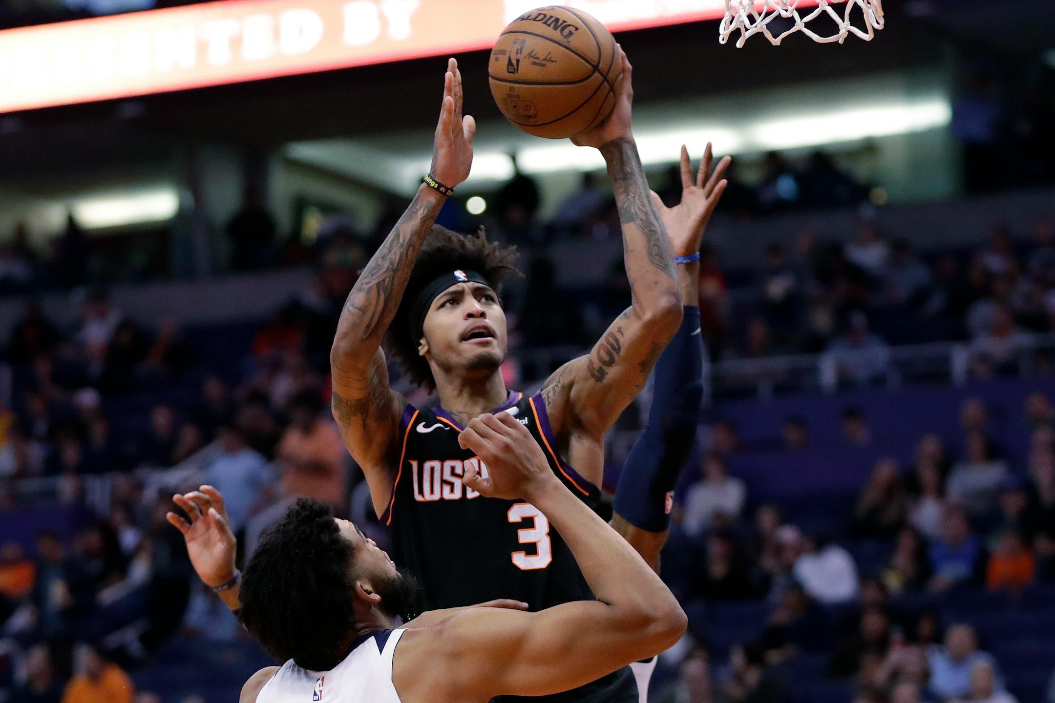Phoenix Suns forward Kelly Oubre Jr. (3) shoots over Minnesota Timberwolves center Karl-Anthony Towns during the second half of an NBA basketball game, Monday, Dec. 9, 2019, in Phoenix. (AP Photo/Matt York)