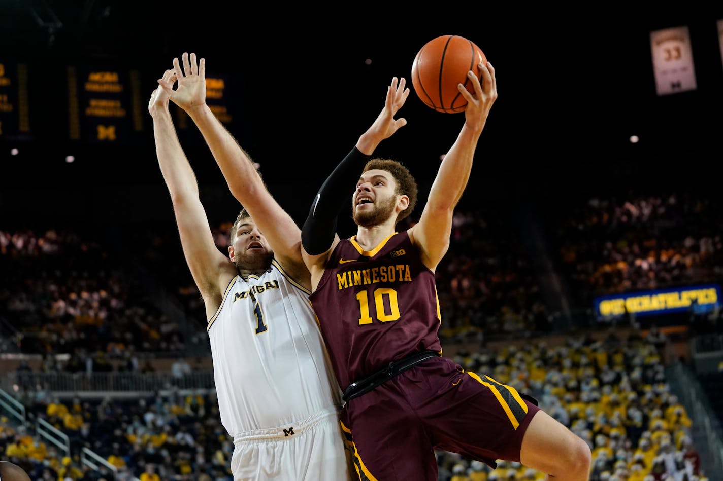 Gophers forward Jamison Battle drives on Michigan's Hunter Dickinson in the first half Saturday night in Ann Arbor.