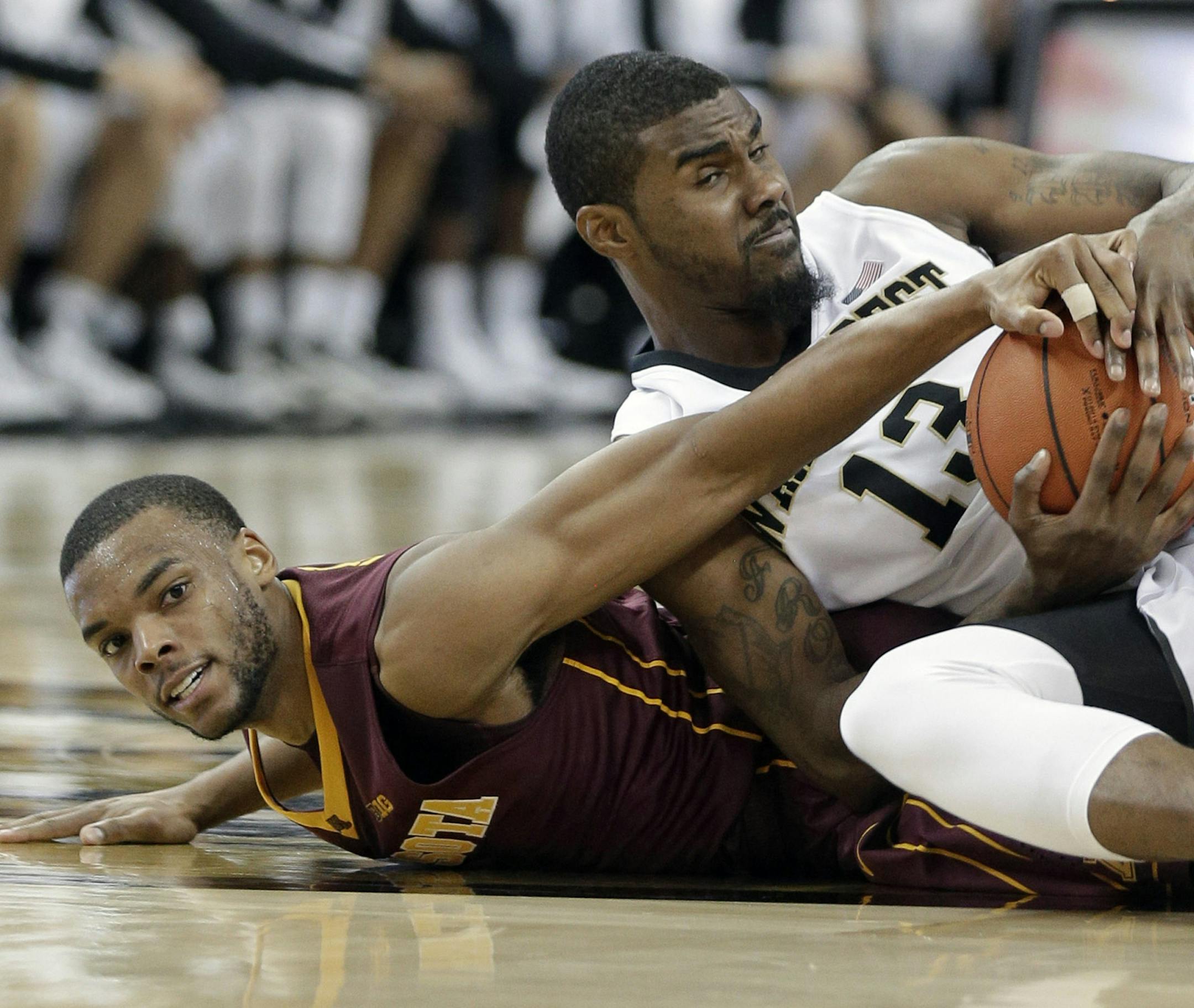 Minnesota's Andre Hollins, left, and Wake Forest's Darius Leonard, right, wrestle for control of a loose ball during the second half of an NCAA college basketball game in Winston-Salem, N.C., Tuesday, Dec. 2, 2014. Minnesota won 84-69. (AP Photo/Chuck Burton)