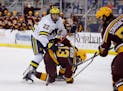 FILE - In this Dec. 8, 2020, file photo, Michigan's Owen Power (22) watches the puck while working against Minnesota's Cullen Munson (13) during an NC