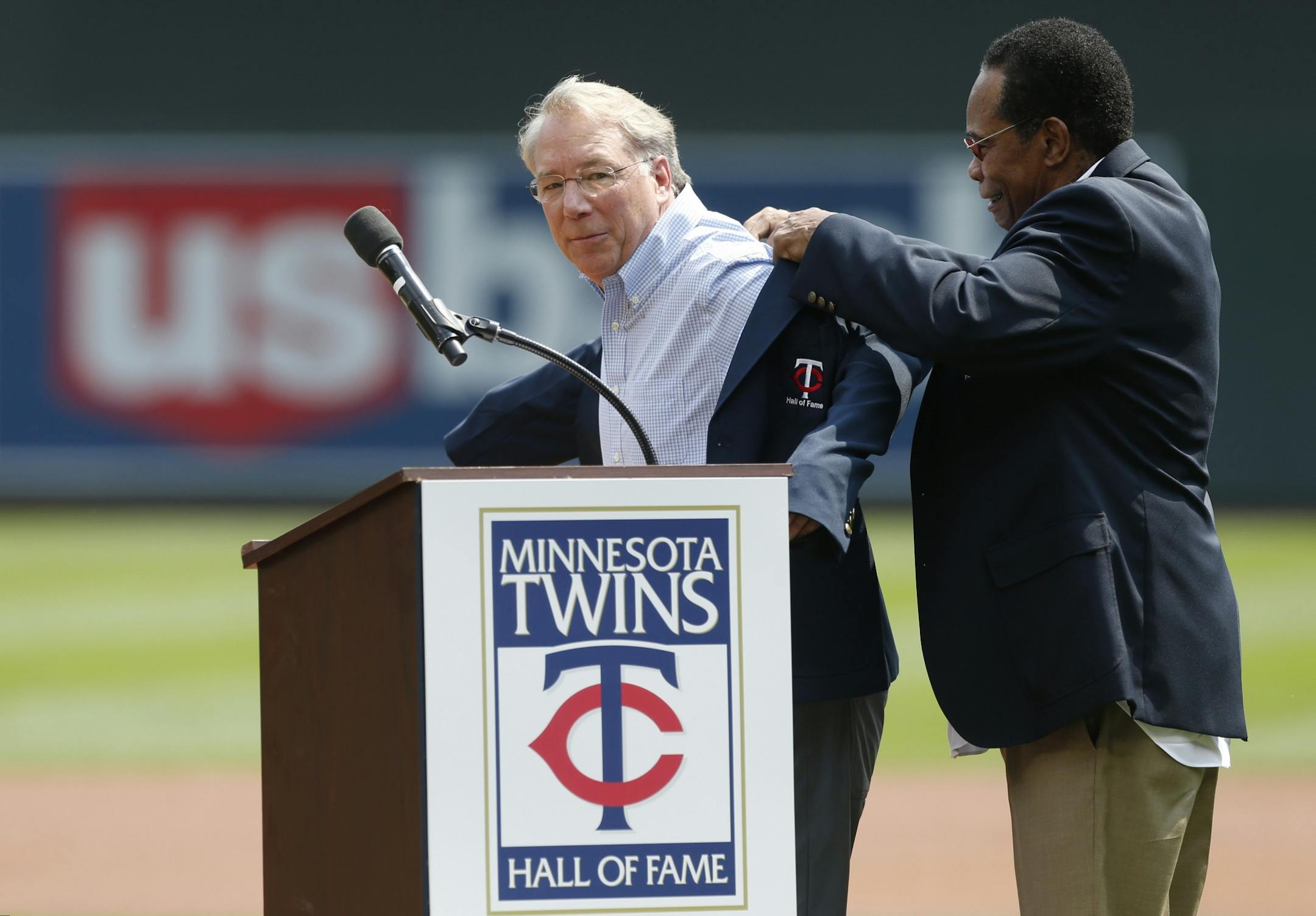 Former Minnesota Twins general manager Andy MacPhail, left, gets help with his new coat presented to him by Twins great Rod Carew as MacPhail was inducted into the Twins' Hall of Fame prior to the baseball game against the Arizona Diamondbacks, Sunday, Aug. 20, 2017, in Minneapolis.