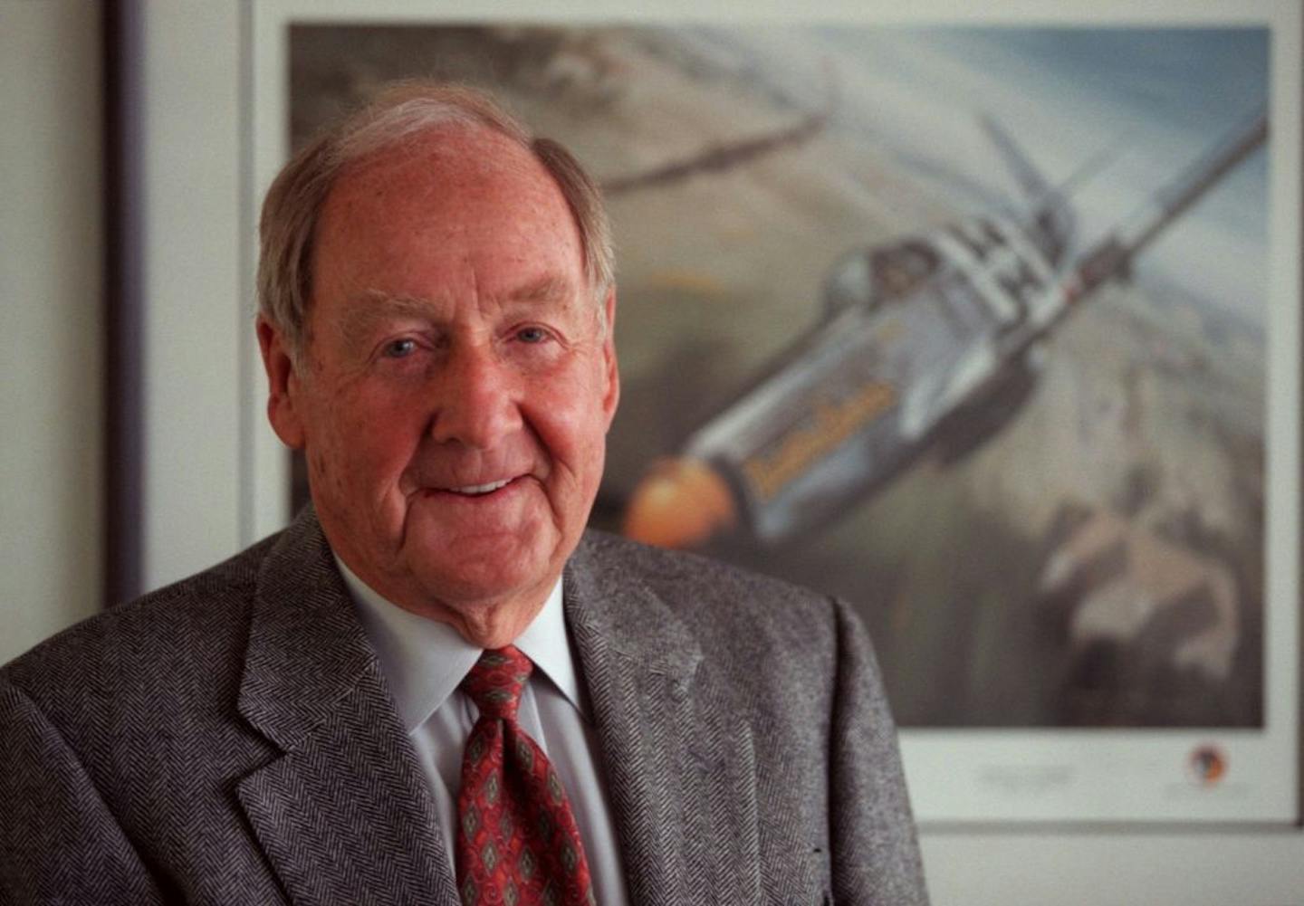 Ken Dahlberg, in front of a painting of a Mustang fighter plane he flew in WWII.