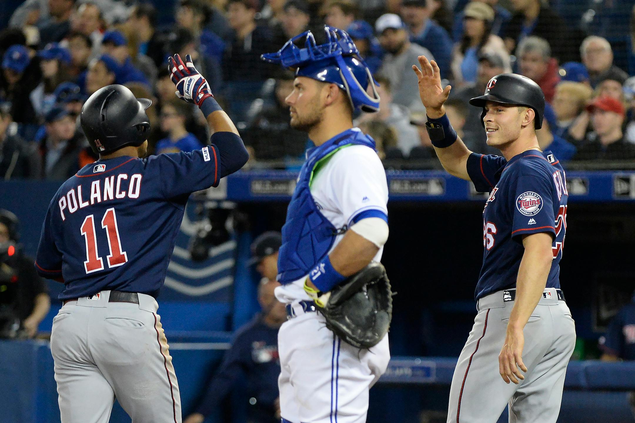 The Twins' Jorge Polanco celebrates his home run with teammate Max Kepler as Toronto catcher Luke Maile looks on during the second inning