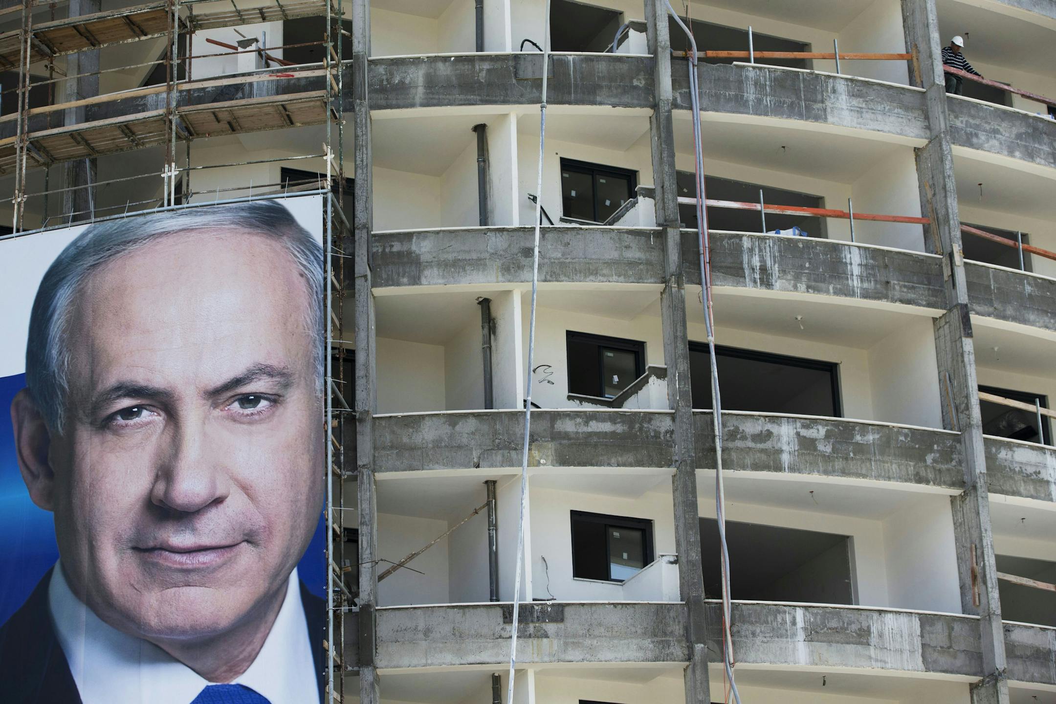 A construction worker looks on as an election campaign billboard of Israel’s Prime Minister Benjamin Netanyahu, Likud party leader, hangs in Tel Aviv, Israel, Sunday, March 8, 2015. Israel will hold a general election on March 17 in which Netanyahu will seek to secure his fourth term as prime minister.