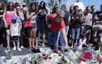 A woman puts flowers near the scene where a truck mowed through revelers in Nice, southern France, Friday, July 15, 2016. A large truck mowed through 
