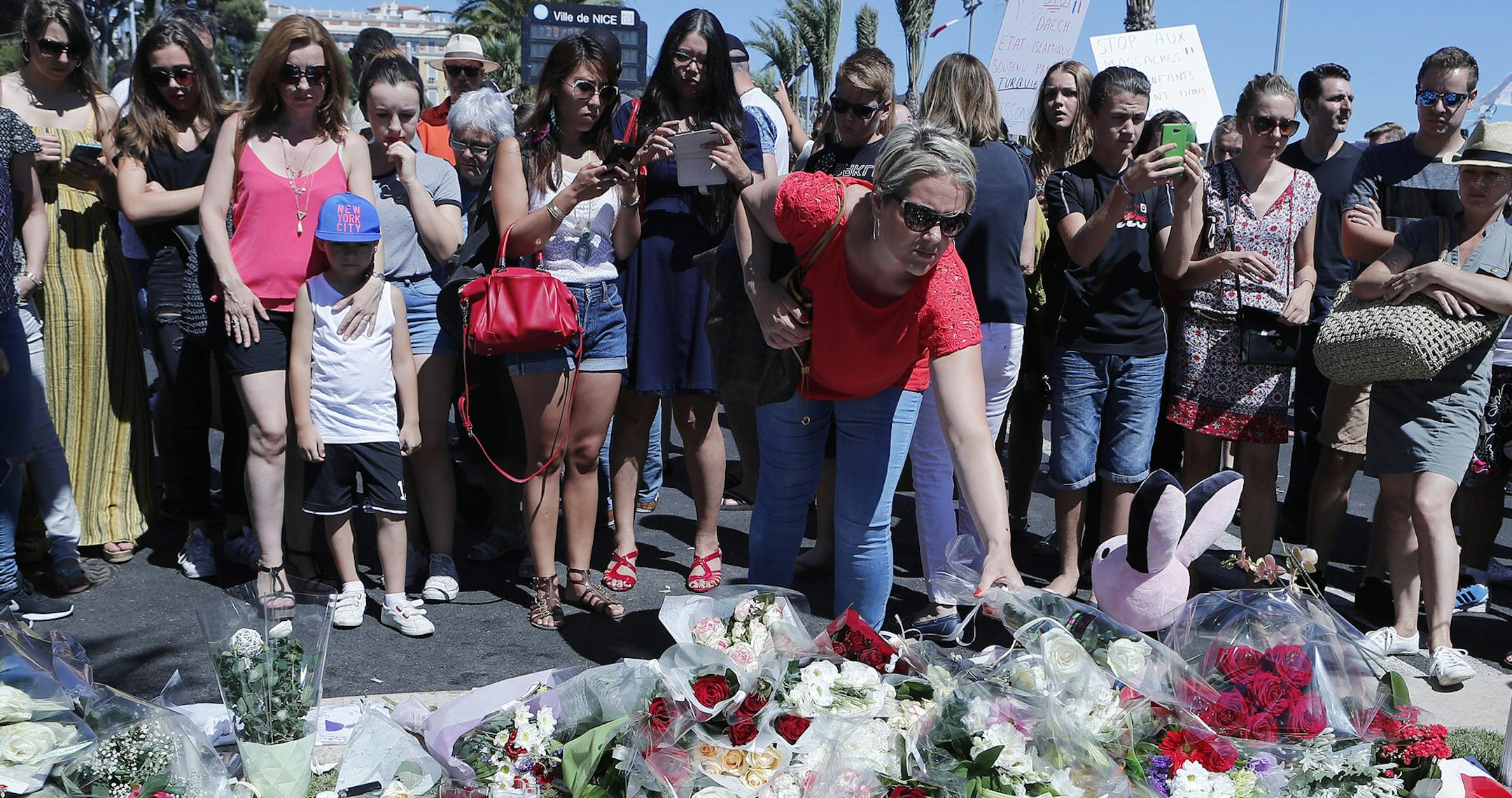 A woman puts flowers near the scene where a truck mowed through revelers in Nice, southern France, Friday, July 15, 2016. A large truck mowed through revelers gathered for Bastille Day fireworks in Nice, killing more than 80 people and sending people fleeing into the sea as it bore down for more than a mile along the Riviera city's famed waterfront promenade. (AP Photo/Francois Mori) ORG XMIT: MIN2016071512191425