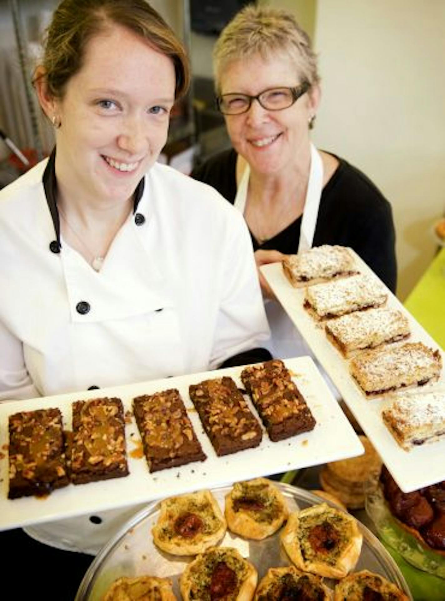 Bars Bakery owners Kara Younkin Viswanathan and Sandi Younkin. Kara is holding Turtle Brownies and Sandi is holding Hungarian Shortbread bars.