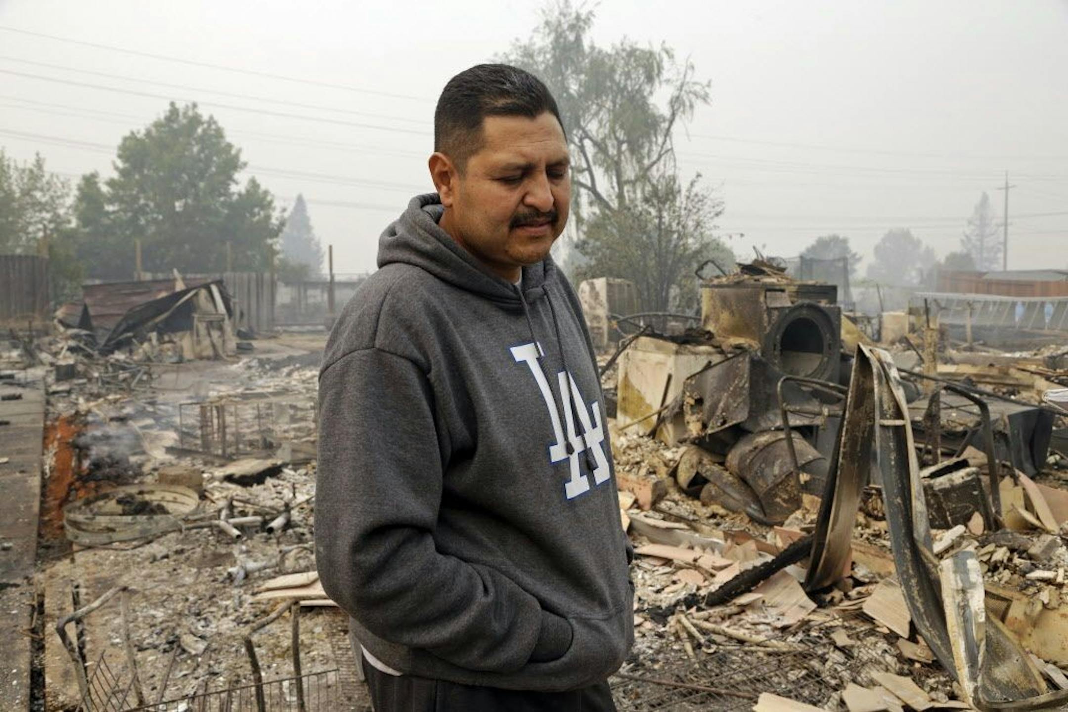 Jose Garnica stands in what remains of his home that was destroyed by fire in the Coffey Park area of Santa Rosa, Calif., on Tuesday, Oct. 10, 2017. An onslaught of wildfires across a wide swath of Northern California broke out almost simultaneously then grew exponentially, swallowing up properties from wineries to trailer parks and tearing through both tiny rural towns and urban subdivisions.