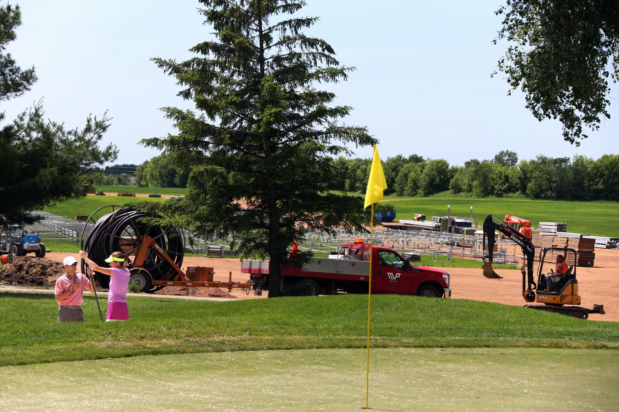 Chris Baisch teaching pro at Hazeltine watched as Lisa Ogren practiced hitting out of the sand trap near the construction site of what will be the international pavilion.
