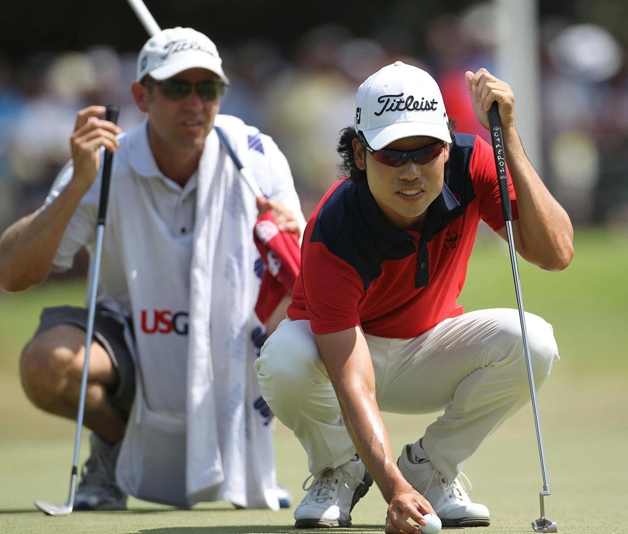Golfer Kevin Na of Seoul, South Korea, lines up a putt on the first hole with his caddy, Kenny Harms, during the third round of the 2014 U.S. Open at Pinehurst No. 2 in Pinehurst, N.C., Saturday, June 14, 2014.