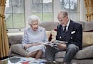 Britain's Queen Elizabeth II and Prince Philip, Duke of Edinburgh look at a homemade wedding anniversary card, given to them by their great-grandchild