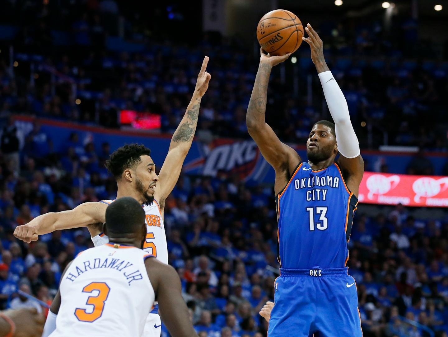 Oklahoma City Thunder forward Paul George (13) shoots over New York Knicks guards Tim Hardaway Jr. (3) and Courtney Lee (5) during the third quarter of an NBA basketball game in Oklahoma City, Thursday, Oct. 19, 2017. Oklahoma City won 105-84. (AP Photo/Sue Ogrocki)