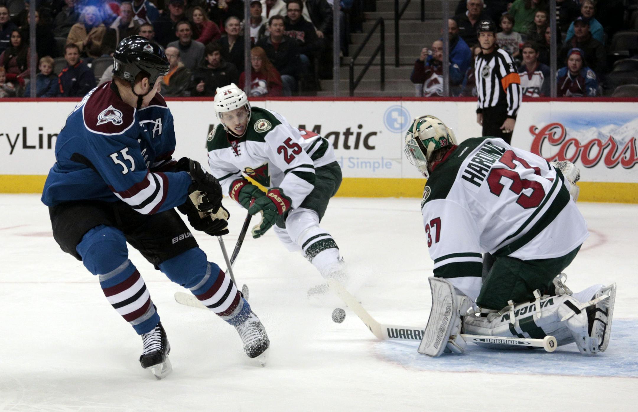 Minnesota Wild goalie Josh Harding (37) stops a shot by Colorado Avalanche left wing Cody McLeod (55) as Wild defenseman Jonas Brodin (25) defends during the first period of an NHL hockey game in Denver on Saturday, Dec. 14, 2013. (AP Photo/Joe Mahoney)