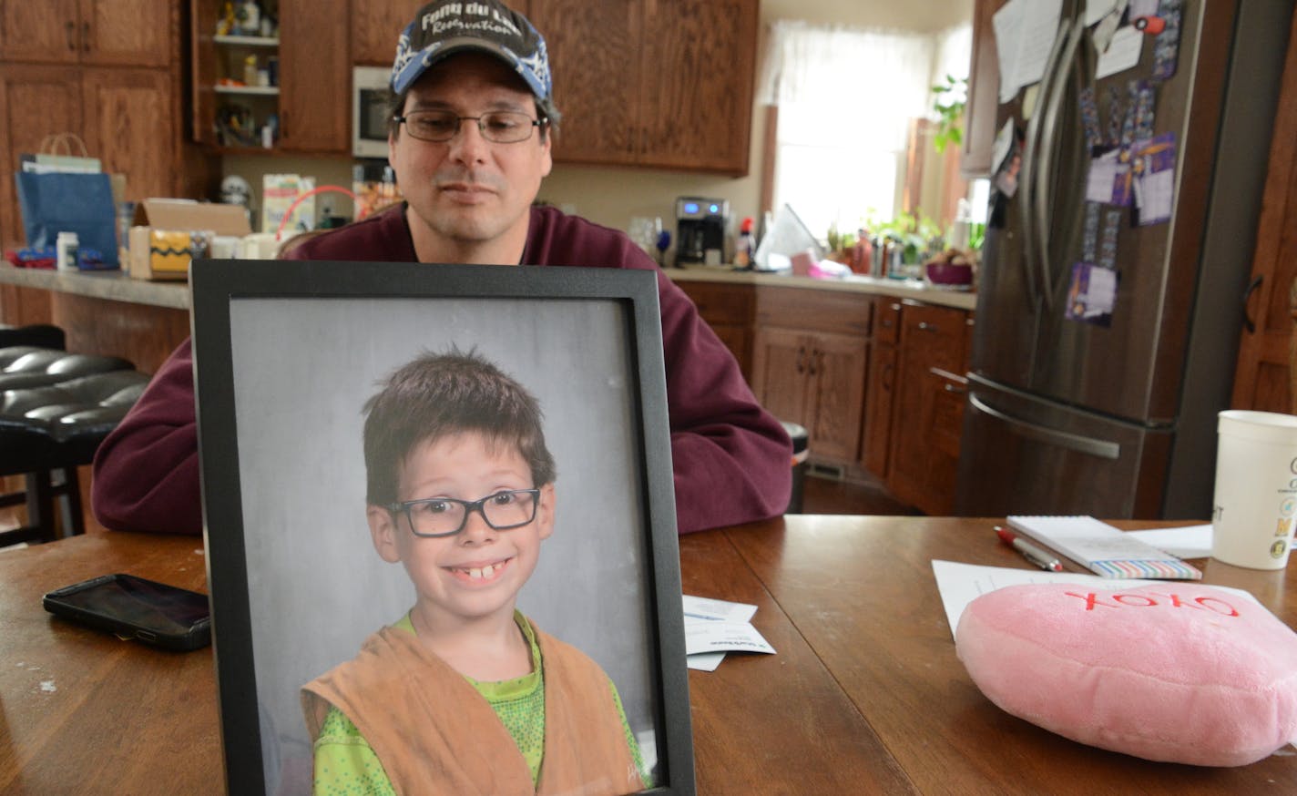 Alan Geisenkoetter Sr. at his family's dining room table looks at a photo of his son, Alan Jr., on Feb. 2, 2018.