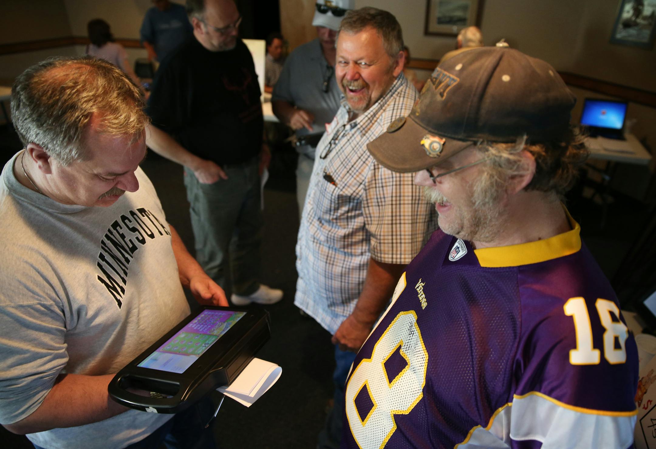 Bar owner Mike Ronning, left, and bartender Tim Sorby tried out an electronic pulltab game with vendor Spanky Kuhlman, in back.