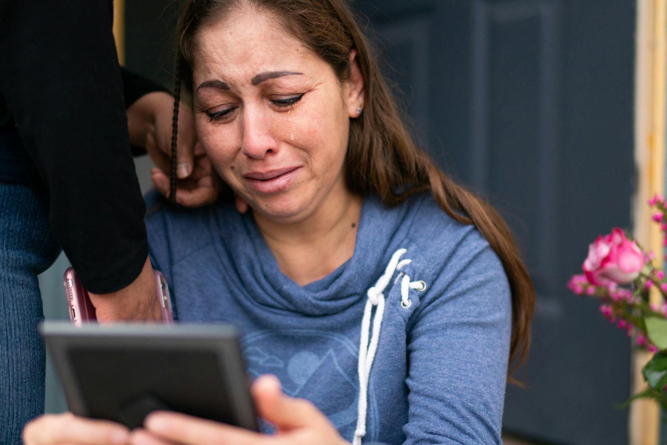 Martha Perea was comforted by a friend in May while clutching a photo of her husband on the steps of the house where the couple lived with their 11-year-old daughter.