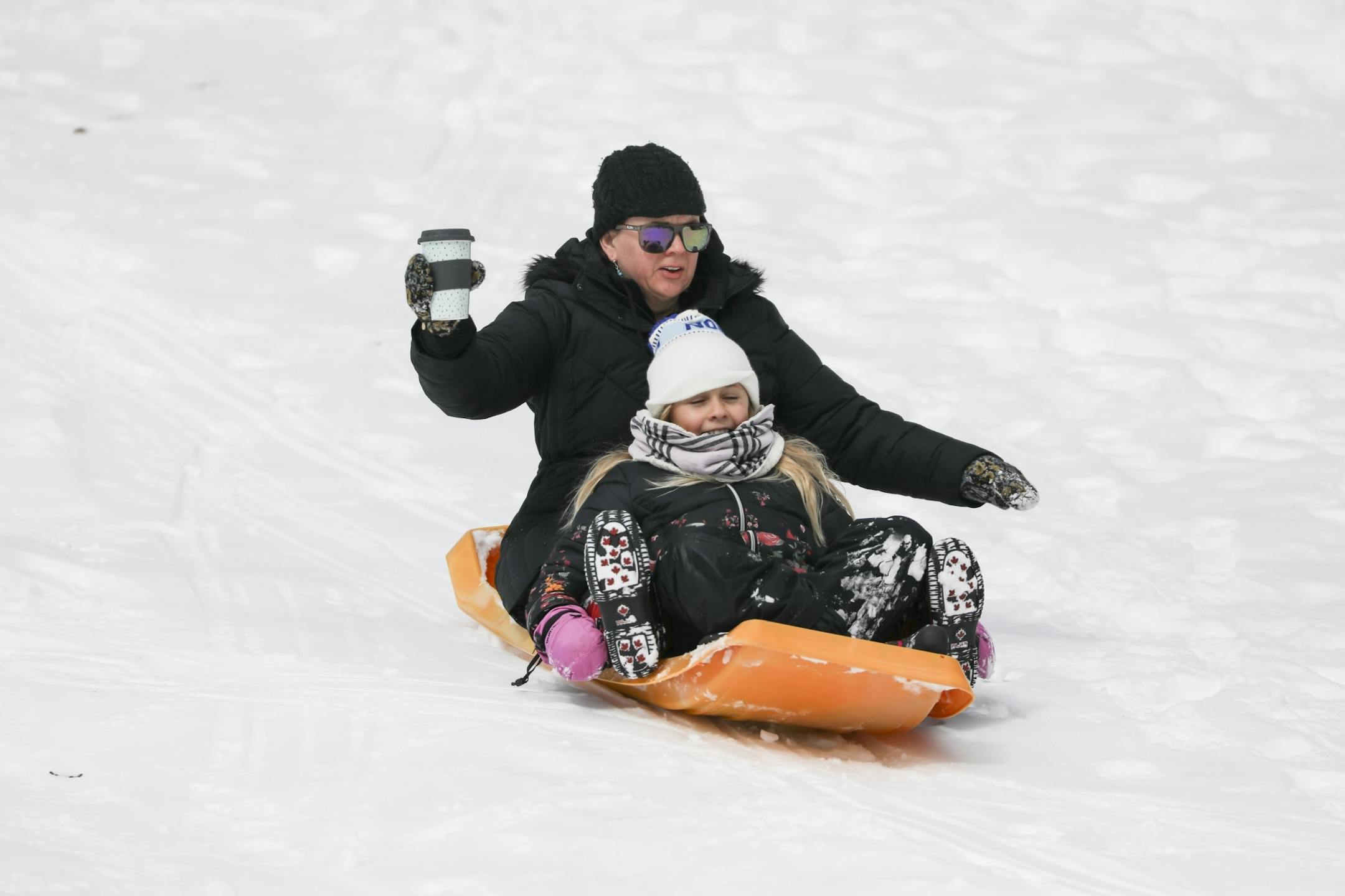 Anne-Marie Fischer held on to her coffee as she rode a sled down a hill at Pearl Park with her daughter Holiday Fischer, 10, on a snow day on Monday, April 16, 2018 in Minneapolis, Minn.