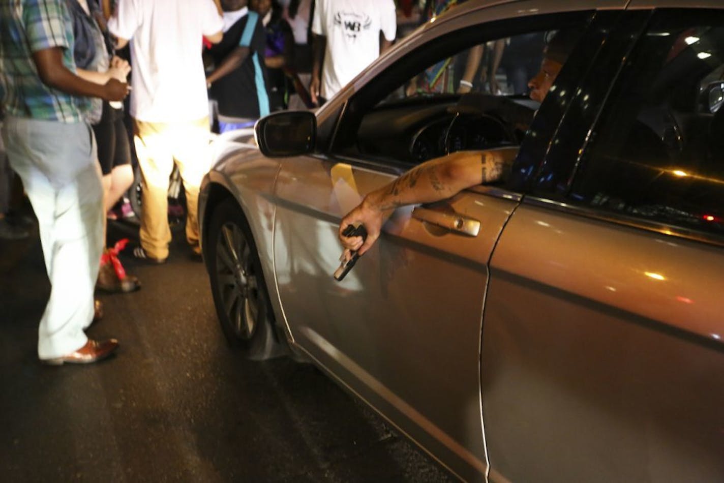 A driver draws his handgun as protesters block traffic at the corner of Tryon Street and Trade Street in Charlotte, N.C., Sept. 21, 2016. After day after Keith Scott�s death at the hands of police triggered a night of violent clashes, Charlotte�s leaders urged calm and contested accounts that Scott was unarmed and holding only a book when he was killed.