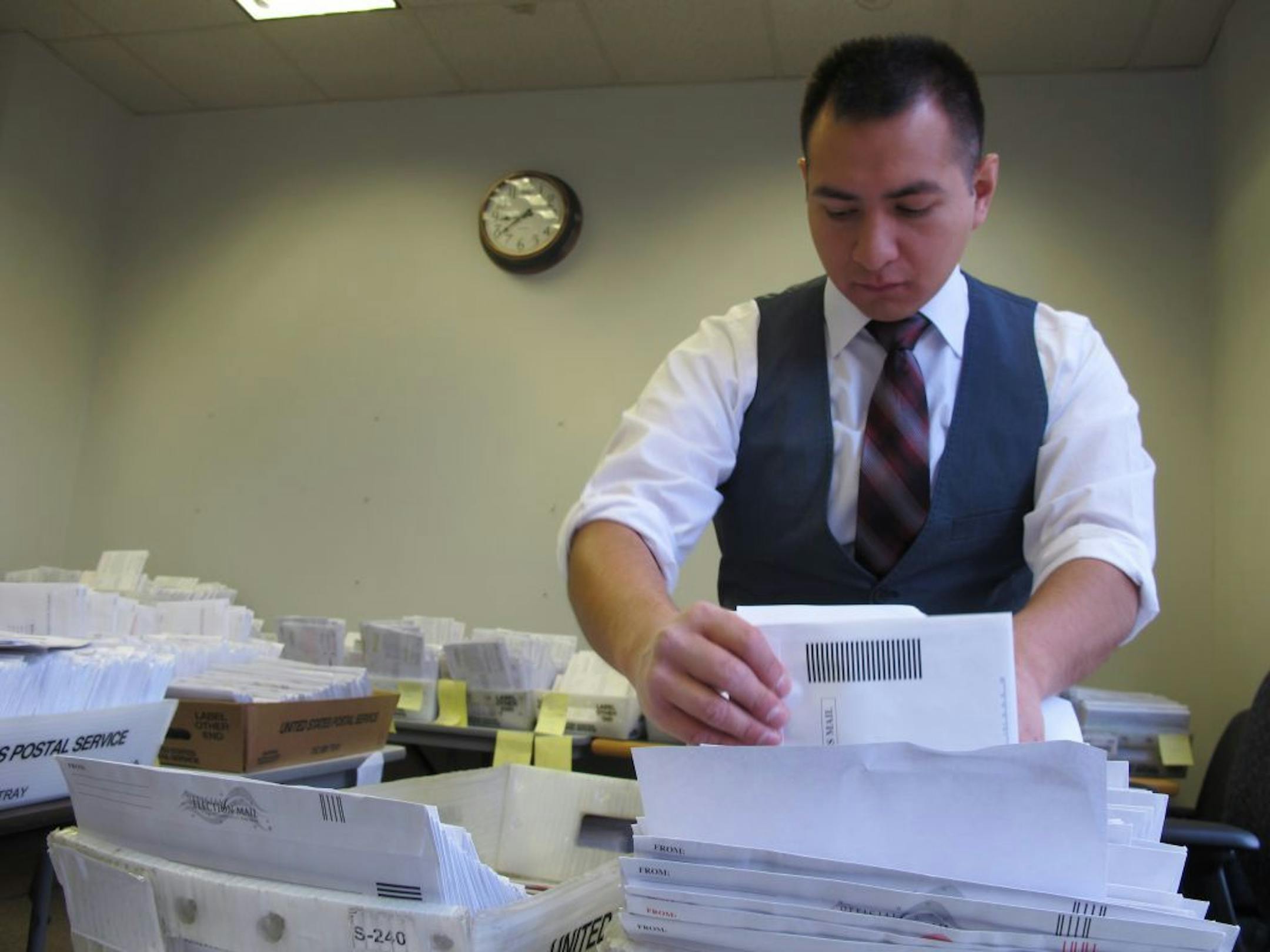 Marcelo Guardiola, a Milwaukee Election Commission staffer, sorts absentee ballots on Monday, Nov. 5, 2012 in Milwaukee. The Election Commission is sorting a record 50,000 absentee ballots this year.