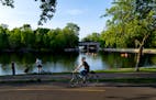 Photo of a woman riding a bicycle in front of a lake