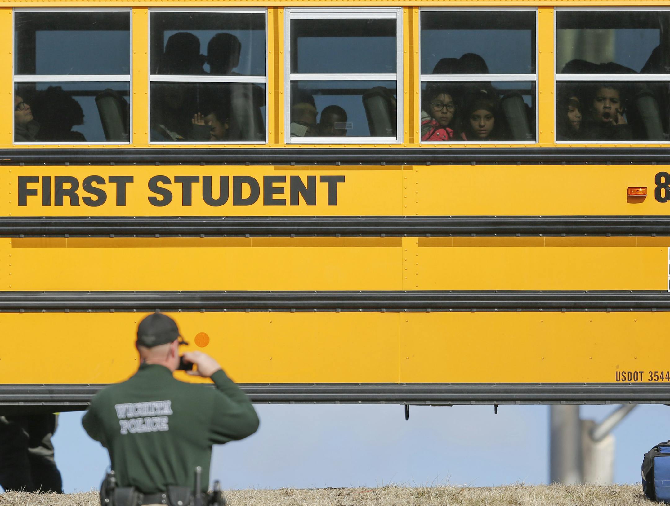 Kids watch a police officer investigate their school bus that collided with another bus on January 26, 2017, in Wichita, Kan.; according to police, 27 children suffered minor injuries. Legislative momentum in a number of states is building behind seat belt requirements on school buses. (Travis Heying/Wichita Eagle/TNS)