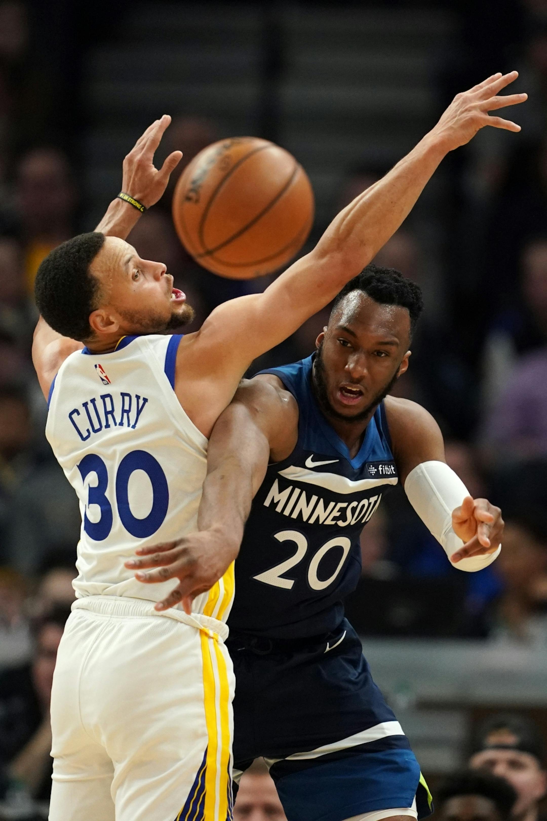Minnesota Timberwolves guard Josh Okogie (20) passed the ball around Golden State Warriors guard Stephen Curry (30) in overtime.