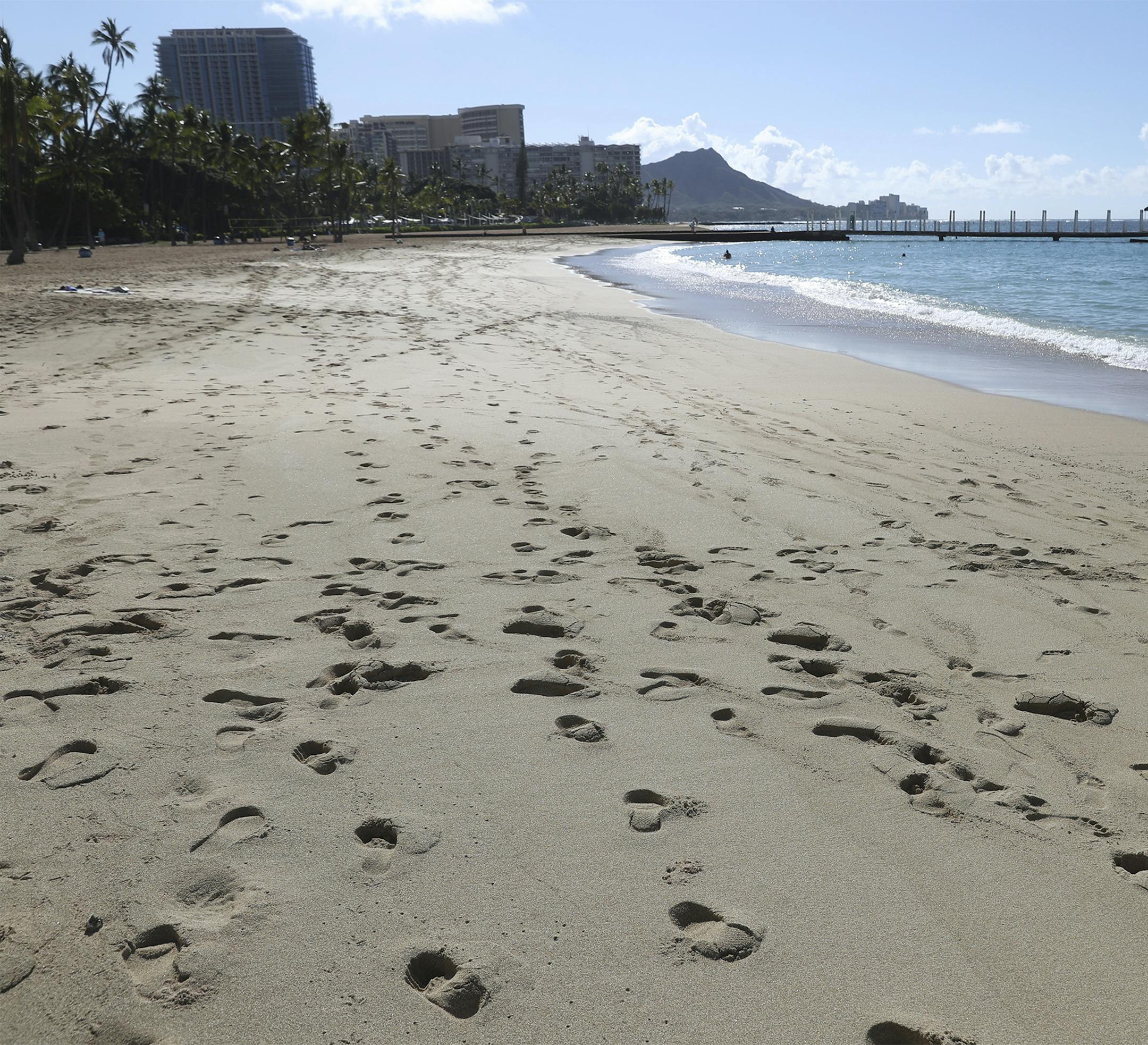A near empty Waikiki Beach is viewed Thursday, Oct. 15, 2020, in Honolulu. A new pre-travel testing program will allow visitors who test negative for COVID-19 to come to Hawaii and avoid two weeks of mandatory quarantine goes into effect Thursday. The pandemic has caused a devastating downturn on Hawaii's tourism-based economy and many are hoping the testing will help the economy rebound. (AP Photo/Marco Garcia)