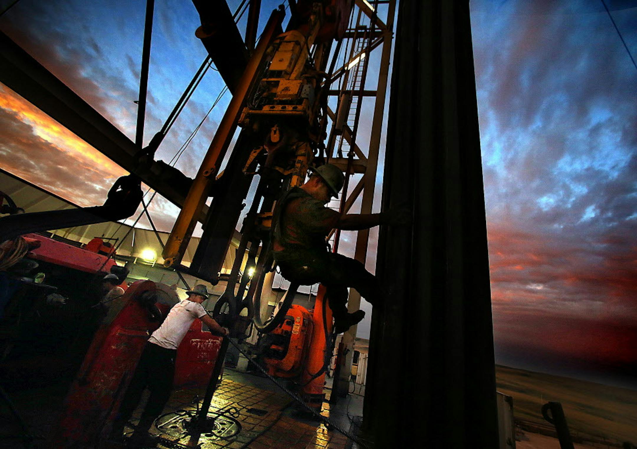 A derrick hand works on a drilling rig structure near Watford CIty, N.D. in December 2013. North Dakota officials said Friday that oil production was up in May despite a drop in active rigs.
