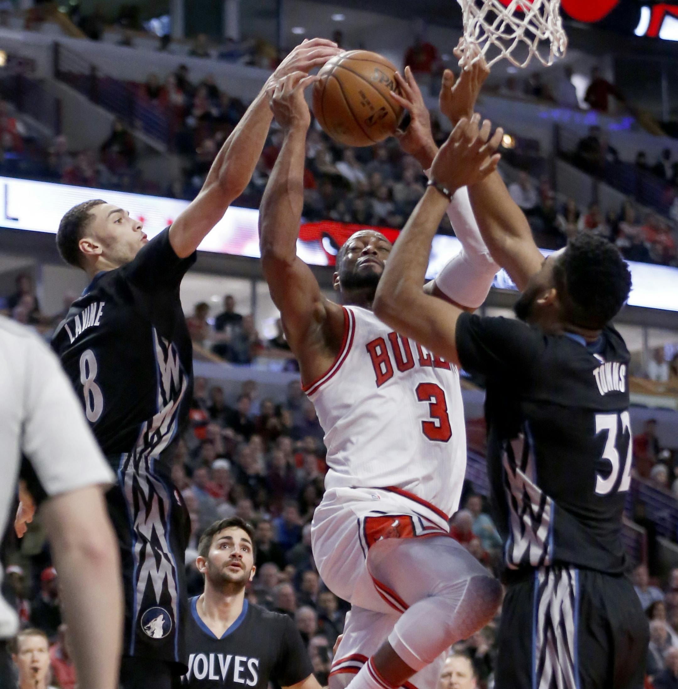 Minnesota Timberwolves' Zach LaVine (8) blocks the shot of Chicago Bulls' Dwyane Wade (3) as Karl-Anthony Towns (32) also defends during the second half of an NBA basketball game Tuesday, Dec. 13, 2016, in Chicago. The Timberwolves won 99-94. (AP Photo/Charles Rex Arbogast)