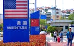 In this May 8, 2019, photo, people walk by a display boards featuring the U.S. and Chinese flags in a special trade zone in Qingdao in eastern China's