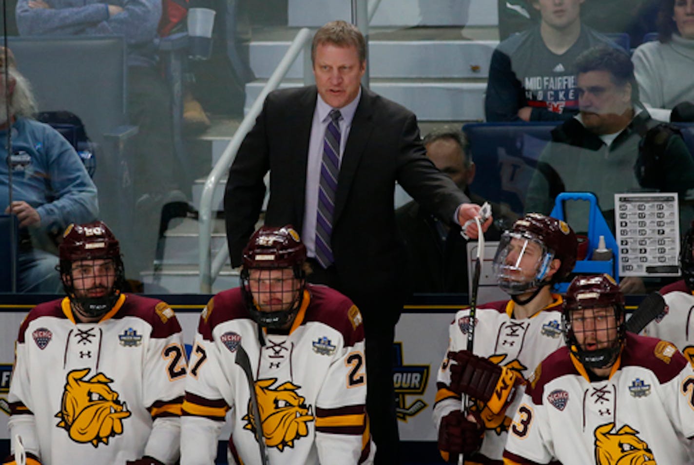 Minnesota-Duluth coach Scott Sandelin stands behind players during the second period of the team's NCAA Frozen Four men's college hockey championship game against Massachusetts, Saturday, April 13, 2019, in Buffalo, N.Y. (AP Photo/Jeffrey T. Barnes)