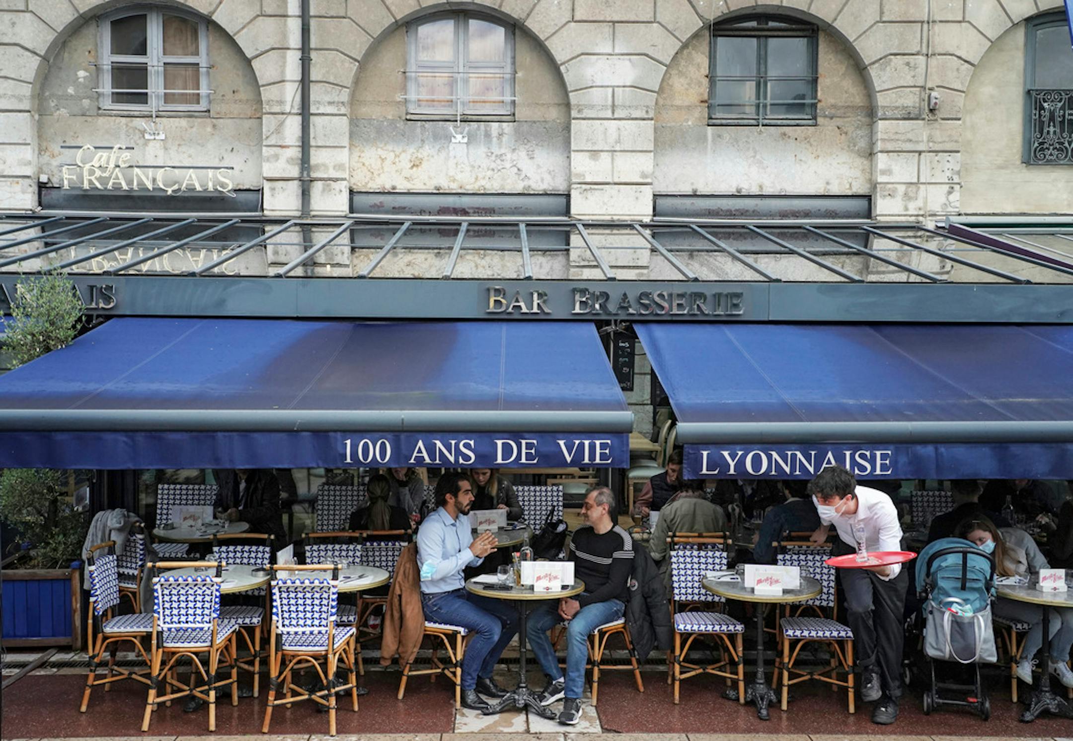 Customers sit at a cafe terrace in Lyon, central France, Wednesday, May, 19, 2021. It's a grand day for the French. Cafe and restaurant terraces are reopening Wednesday after a pandemic shutdown of more than six months deprived people of what feels like the essence of life in France. (AP Photo/Laurent Cipriani)