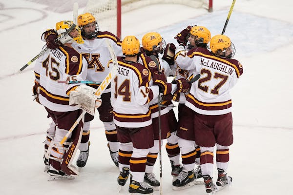 Minnesota defenseman Ryan Johnson (23) was mobbed by his teammates after he scored from down the ice on an empty net in the third period. ] ANTHONY SO