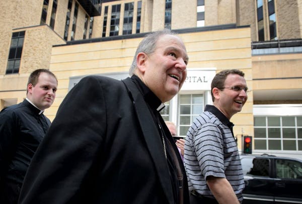 New interim Archbishop Bernard Hebda, center, walks with Deacon John Powers, left and Auxiliary Bishop Andrew Cozzens, right, out of St. John The Evan