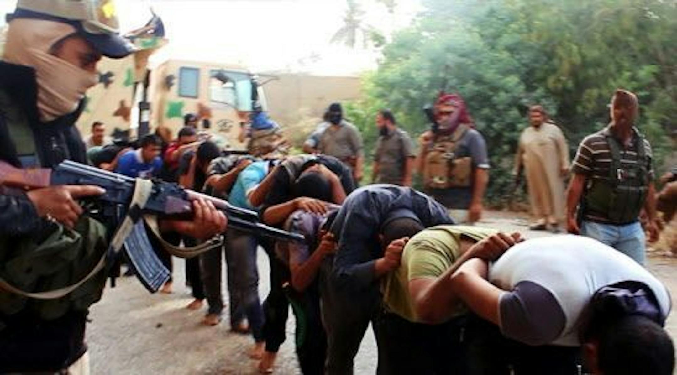 This image posted on a militant website on Saturday, June 14, 2014, which has been verified and is consistent with other AP reporting, appears to show militants from the al-Qaida-inspired Islamic State of Iraq and the Levant (ISIL) leading away captured Iraqi soldiers dressed in plain clothes after taking over a base in Tikrit, Iraq.