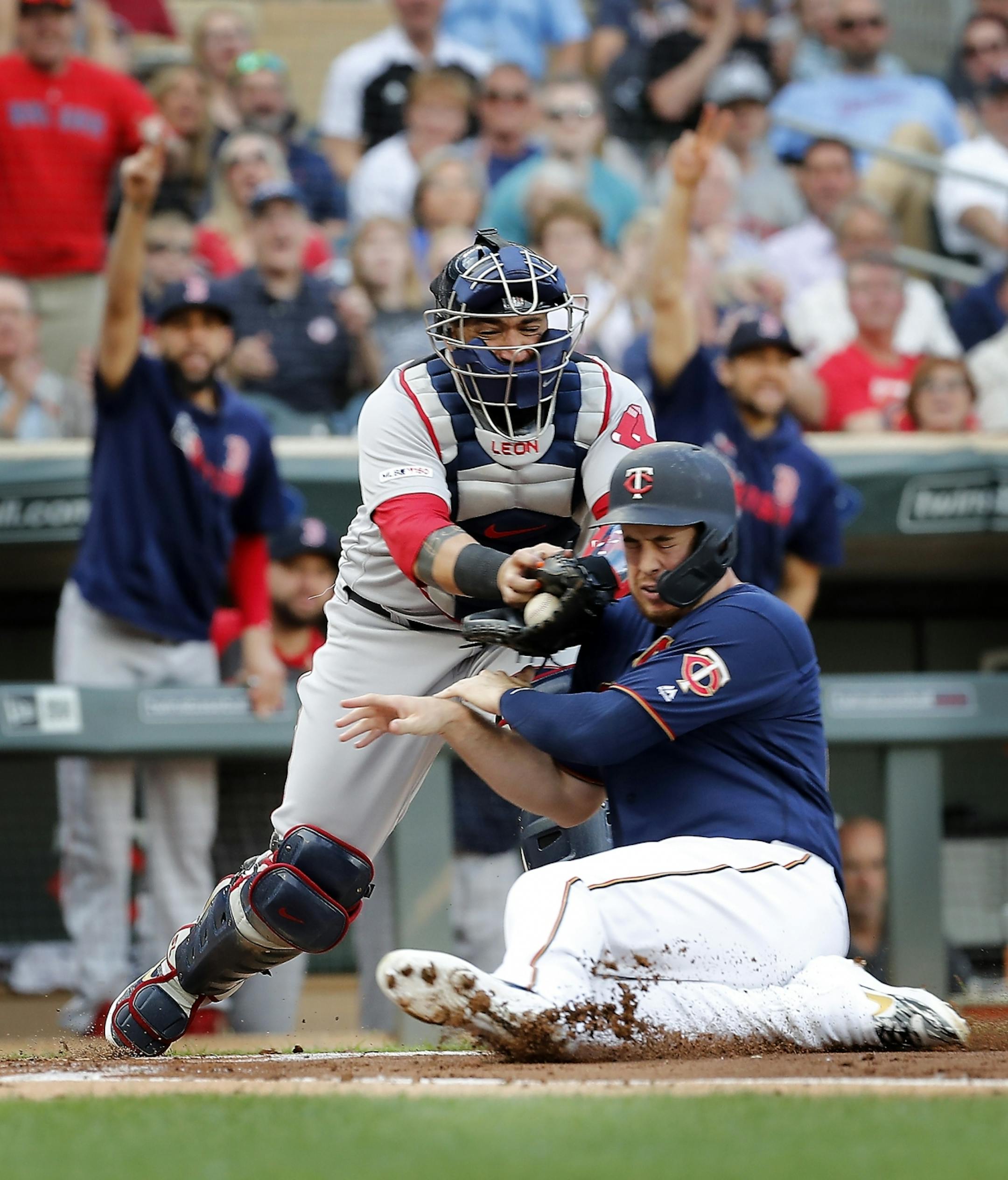 Minnesota Twins first baseman C.J. Cron (24) is tagged out at home plate by Boston Red Sox catcher Sandy Leon (3) in the first inning.